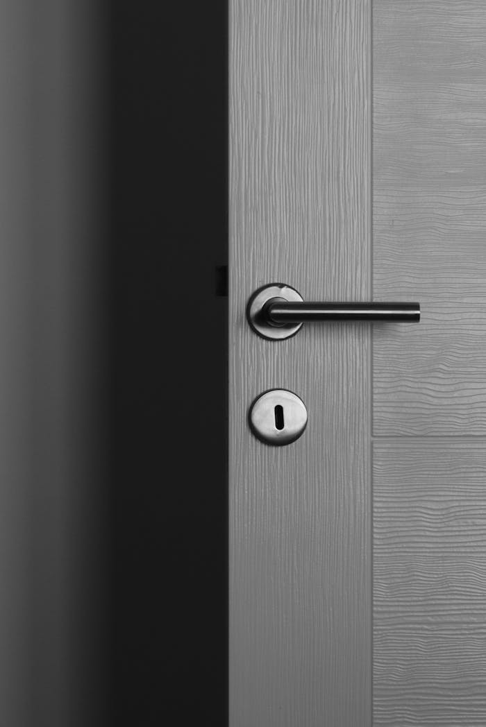 Close-up of a modern gray door with a sleek metal handle and keyhole.